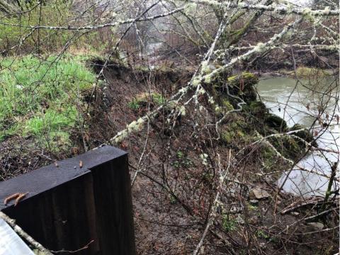 A photo taken from the viewpoint of the highway. It shows a washed out river bank next to a river.