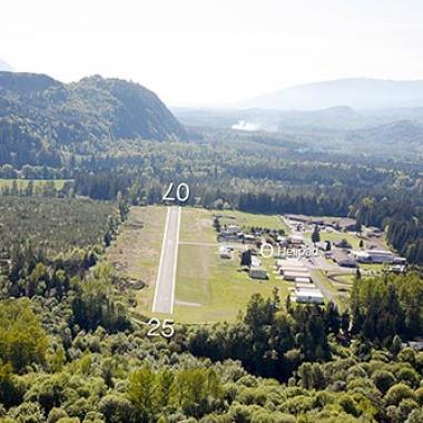 Concrete Airport Runway nestled inbetween flat grasslands and trees. 