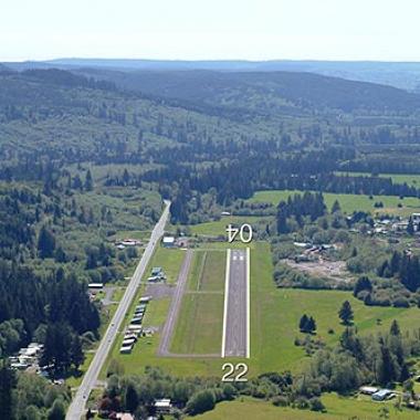 Forks Municipal airport runway located on flat grasslands with trees surrounding.