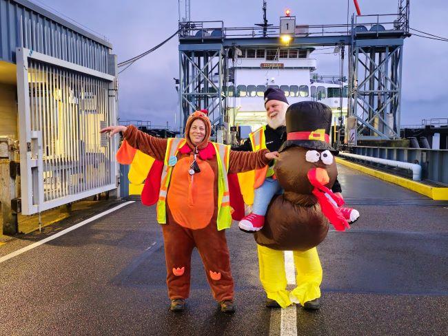 Two people in fun turkey costumes on the dock at Vashon terminal standing in front of the ferry Issaquah